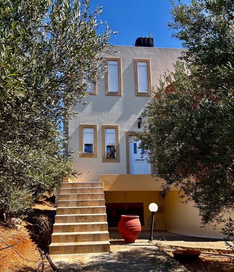 Ancestral Earth guesthouse op Oost-Kreta, omringd door olijfbomen en zonlicht – een plek voor rust, verbinding en natuurlijke eenvoud.